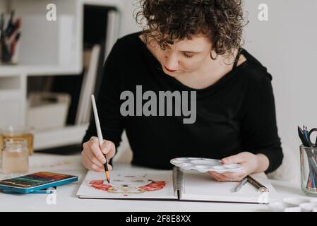 LEEDS, ROYAUME-UNI - 03 mars 2021 : artiste féminine travaillant sur un dessin coloré d'un portrait féminin dans un carnet d'esquisses. Banque D'Images