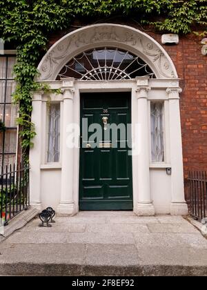 DUBLIN, IRLANDE - 24 juillet 2019 : porte d'entrée décorative d'une maison de ville géorgienne à Dublin, Irlande. Porte entourée de lierre. Banque D'Images