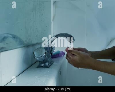 Enfants masqués se laver les mains pendant une pandémie de coronavirus. Le port et l'utilisation d'assainisseur du masque de lavage des mains sont recommandés par l'organisation mondiale de la santé. Banque D'Images