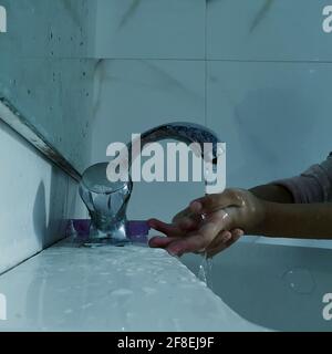 Enfants masqués se laver les mains pendant une pandémie de coronavirus. Le port et l'utilisation d'assainisseur du masque de lavage des mains sont recommandés par l'organisation mondiale de la santé. Banque D'Images