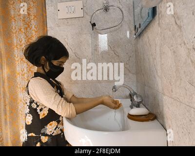 Enfants masqués se laver les mains pendant une pandémie de coronavirus. Le port et l'utilisation d'assainisseur du masque de lavage des mains sont recommandés par l'organisation mondiale de la santé. Banque D'Images