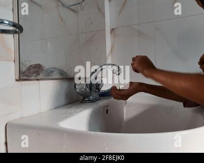 Enfants masqués se laver les mains pendant une pandémie de coronavirus. Le port et l'utilisation d'assainisseur du masque de lavage des mains sont recommandés par l'organisation mondiale de la santé. Banque D'Images