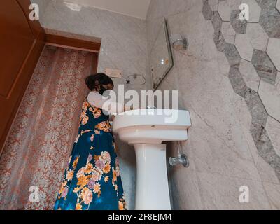 Enfants masqués se laver les mains pendant une pandémie de coronavirus. Le port et l'utilisation d'assainisseur du masque de lavage des mains sont recommandés par l'organisation mondiale de la santé. Banque D'Images