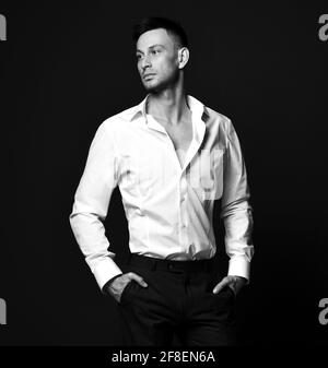 Portrait en noir et blanc d'un jeune homme d'affaires sûr de lui-même en officiel pantalon de costume et chemises regardant de côté Banque D'Images