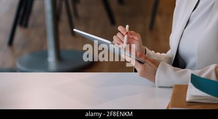 Gros plan femme d'affaires tient le stylet dessin sur une tablette numérique sur le lieu de travail Banque D'Images