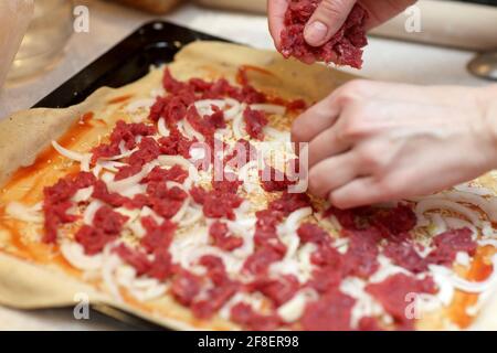 Le chef cuisinier met sur une pizza la viande hachée Banque D'Images