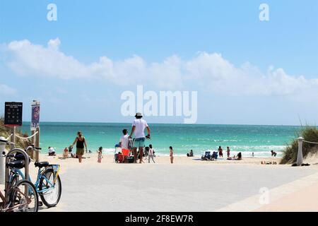Vélos garés à l'entrée de la plage. Touristes, familles et brise-roches à South Pointe Beach à Miami Beach, Floride. Vacances de printemps 2021 Banque D'Images