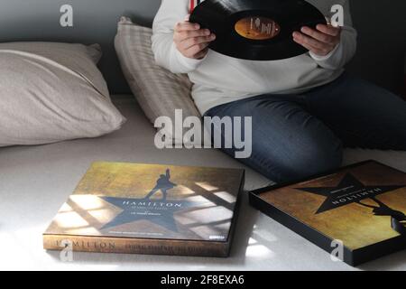 Femme à la recherche et à l'écoute du disque LP original Broadway Cast Recording Vinyl Record de Hamilton dans sa chambre. Banque D'Images