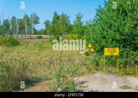 Signe jaune marquant les matières radioactives enfouies dans la zone d'exclusion de Tchernobyl En Ukraine Banque D'Images