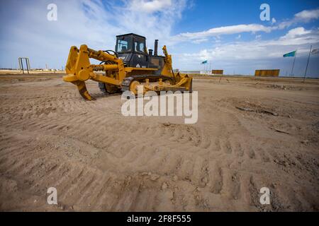 Aktau, Kazakhstan. Développement de la zone économique libre. Préparation à la construction du port maritime. Le bulldozer aplatit la surface du sol. Banque D'Images