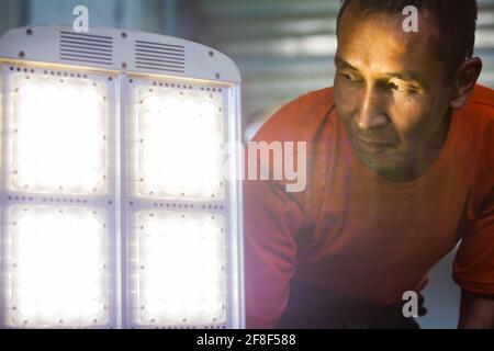 Aktau, Kazakhstan - 19 mai 2012: Travailleur d'homme asiatique regardant le panneau lumineux LED d'éclairage de rue. Voyant ALLUMÉ. Les feux de détresse (à droite, au centre) sont hors de f Banque D'Images