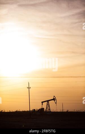 Silhouette de cric de pompage d'huile sur ciel jaune. Coucher et soleil. Zhanaozen, Kazakhstan. Banque D'Images