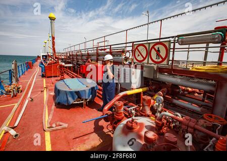 Aktau, Kazakhstan: Mer Caspienne, terminal de chargement d'Aktau. Gros plan sur le comptoir « Anbutane » du navire-citerne GPL et les tuyaux d'incendie. Travailleur avec radio au centre. Banque D'Images