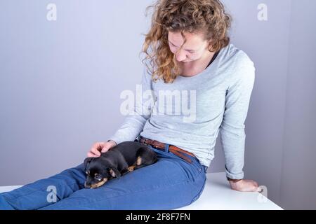 Détail d'une belle femme avec des lunettes et des cheveux bruns, assis souriant avec un chiot Jack Russel Terrier sur ses jambes Banque D'Images