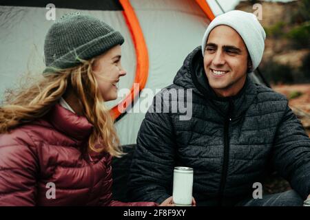 Couple caucasien souriant l'un à l'autre bavardant en campant montagne Banque D'Images