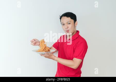 Portrait de Shock and Wow le jeune homme asiatique apprécie les nouilles. Dîner concept. Banque D'Images