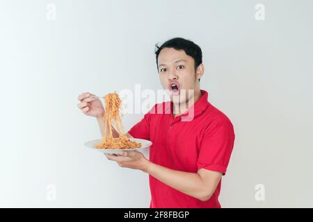 Portrait de Shock and Wow le jeune homme asiatique apprécie les nouilles. Dîner concept. Banque D'Images