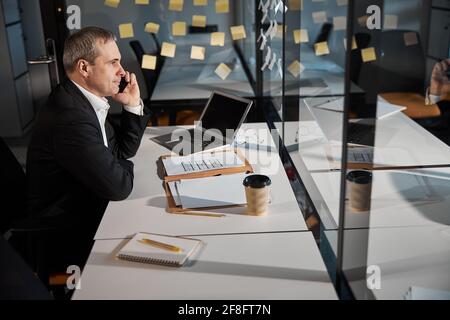Un homme d'affaires de bonne qualité qui parle au téléphone portable au travail Banque D'Images