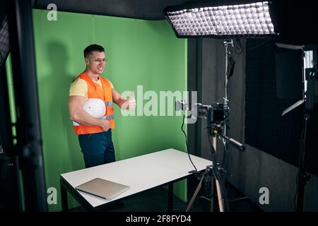 Joyeux constructeur d'enregistrer des vidéos avec un smartphone et de donner des pouces vers le haut Banque D'Images