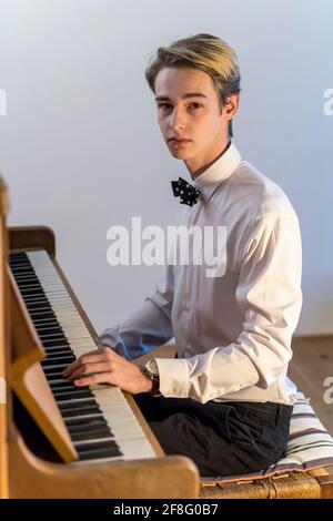 chemise blanche garçon avec noeud papillon joue du piano à la maison Banque D'Images