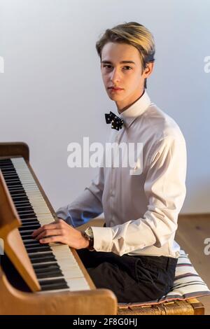 chemise blanche garçon avec noeud papillon joue du piano à la maison Banque D'Images