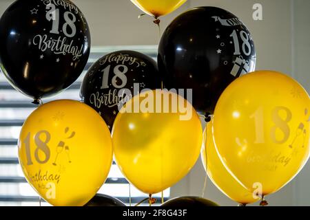 Ballons remplis d'hélium noir et or avec inscription du 18e anniversaire Banque D'Images