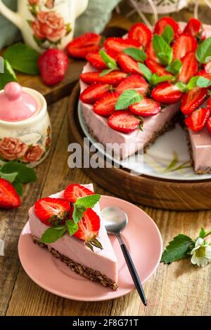 Dessert estival sans cuisson sans gluten, menus d'anniversaire. Cheesecake à la fraise sur une granola avec des fraises fraîches sur une table en bois rustique Banque D'Images