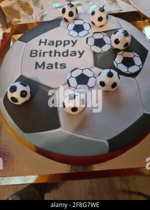 Gâteau d'anniversaire sportif amusant et charmant. Design avec le terrain de football. Chaussures, bâtiments, journée sportive. Gâteau, crème. Champ vert. Gâteau d'anniversaire pour un sport Banque D'Images