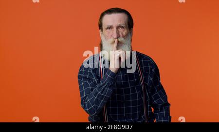 L'homme barbu âgé appuie l'index sur les lèvres fait le silence le signe gestuel ne dit pas secret Banque D'Images