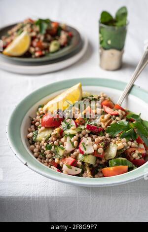 Vue latérale de deux bols avec une salade de couscous de blé entier végétalien saine avec des légumes frais au citron sur fond blanc, avec espace pour les copies Banque D'Images