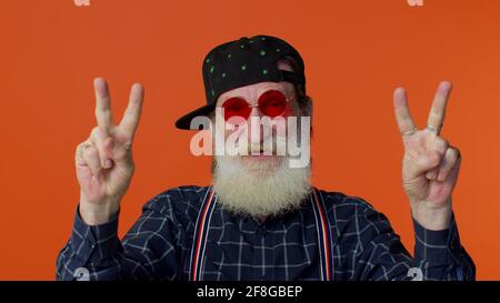 Homme barbu senior montrant le signe de la victoire, espérant le succès et la victoire, faisant le geste de paix et souriant Banque D'Images