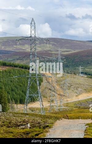 Pylônes de distribution d'énergie aérienne transportant l'électricité haute tension du Ferme éolienne Farr montrant l'industrialisation de la campagne Banque D'Images