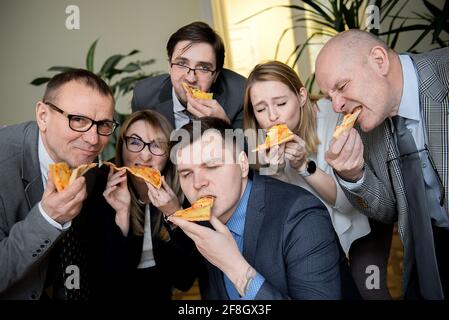 Affaires, alimentation, déjeuner et personnes concept - happy business team eating pizza in office Banque D'Images