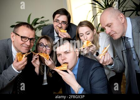 Affaires, alimentation, déjeuner et personnes concept - happy business team eating pizza in office Banque D'Images