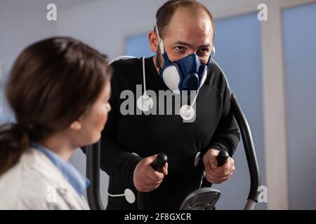 Un chercheur de fitness surveille les performances de l'athlète avec des capteurs fixés pour la course à pied sur un entraînement multisport. Scientifique de fitness en laboratoire de sciences du sport. Electrodes EKG sur le corps. Banque D'Images