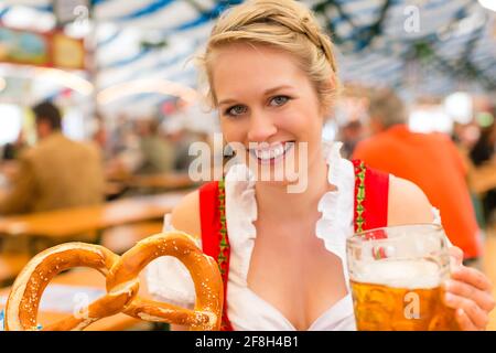 Jeune femme en habits traditionnels bavarois dirndl - ou tracht - sur un festival ou dans une tente à bière Oktoberfest Banque D'Images