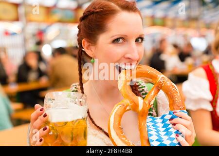 Jeune femme en habits traditionnels bavarois dirndl - ou tracht - sur un festival ou dans une tente à bière Oktoberfest Banque D'Images