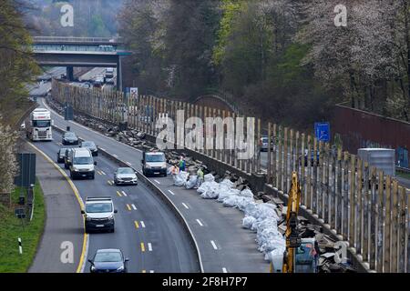 Sanierung Laermschutzwand auf der A52. Mehrere Arbeiter in Schutzanzuegen und Atemmaske verfrachten den Inhalt von Schallschutzelementen in weisse SAE Banque D'Images