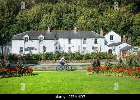 Un cycliste passant devant les cottages patrimoniaux dans les jardins subtropicaux de Trenance à Newquay, en Cornouailles. Banque D'Images