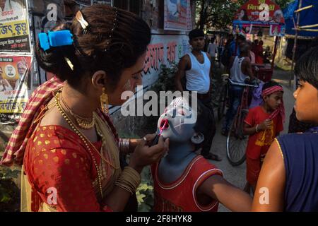 Bardhaman, Inde. 13 avril 2021. Un cosplayer donne une touche finale de rouge à lèvres sur un jeune dévot pendant le festival Gajan. Gajan est un festival hindou célébré principalement dans le Bengale occidental ainsi que dans le sud du Bangladesh. Le festival est associé à la dévotion de Lord Shiva. Les gens célèbrent en réalisant des rituels tels que la peinture du visage et le cosplaying. Les dévotés s'habillent comme des personnages mythologiques hindous et exécutent diverses histoires mythologiques porte à porte. (Photo par Tamal Shee/SOPA Images/Sipa USA) crédit: SIPA USA/Alay Live News Banque D'Images