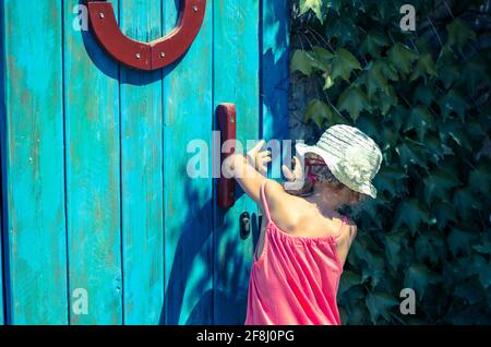 curieuse petite fille essayant d'ouvrir une porte en bois verrouillée Banque D'Images