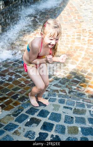 petite fille blonde jouant avec de l'eau Banque D'Images