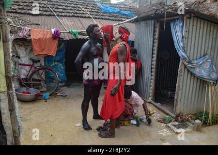 Bardhaman, Inde. 13 avril 2021. Un dévot est vu peindre un autre dévot pendant le festival de Gajan. Gajan est un festival hindou célébré principalement dans le Bengale occidental ainsi que dans le sud du Bangladesh. Le festival est associé à la dévotion de Lord Shiva. Les gens célèbrent en réalisant des rituels tels que la peinture du visage et le cosplaying. Les dévotés s'habillent comme des personnages mythologiques hindous et exécutent diverses histoires mythologiques porte à porte. Crédit : SOPA Images Limited/Alamy Live News Banque D'Images