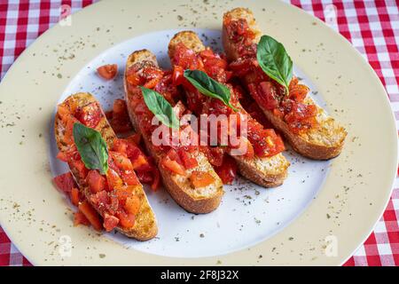 Des hors-d'œuvre italiens salés à base de tomates ou de la bruschetta sur des tranches de baguette de basilic grillées. Banque D'Images