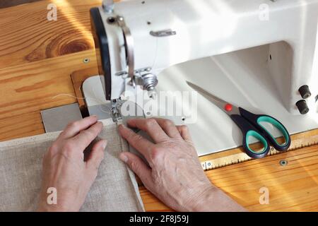 Femme d'âge moyen mains linge de couture tissu sur la machine à coudre, de dessus la vue de dessus de dessus de dessus, l'artisanat, la mode lente, les moments de la vie quotidienne et ECO Banque D'Images