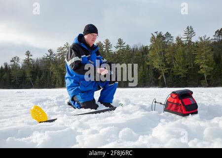 Homme pêche sur glace sur un lac du nord du Minnesota sur un matin d'hiver Banque D'Images