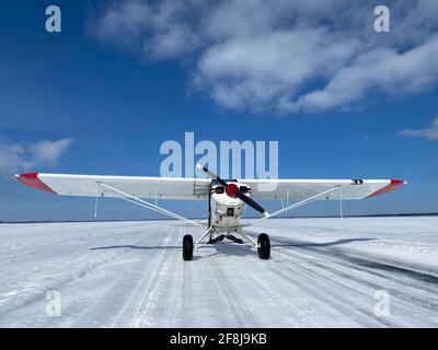 Un petit avion à moteur unique est installé sur une piste d'atterrissage sur glace Sur un lac du nord du Minnesota par une belle journée d'hiver Banque D'Images