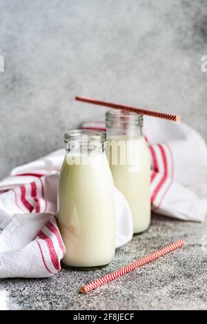 Deux bouteilles de lait et de pailles à boire sur la table à un torchon Banque D'Images
