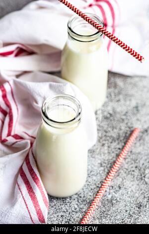 Deux bouteilles de lait et de pailles à boire sur la table à un torchon Banque D'Images