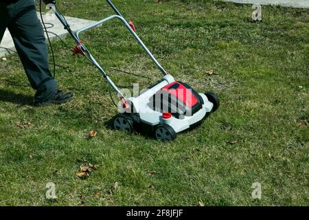 Aération avec scarificateur. Utiliser un scarificateur dans le jardin pour améliorer la qualité de la pelouse au printemps. Un travailleur, Gardener, qui fait fonctionner l'aération du sol Banque D'Images